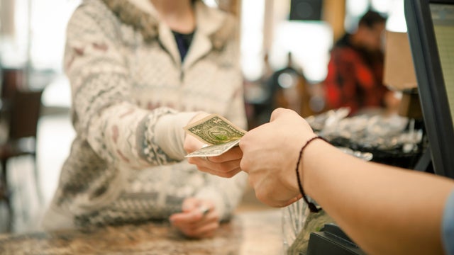Female customer handing payment to waiter over cafe counter 