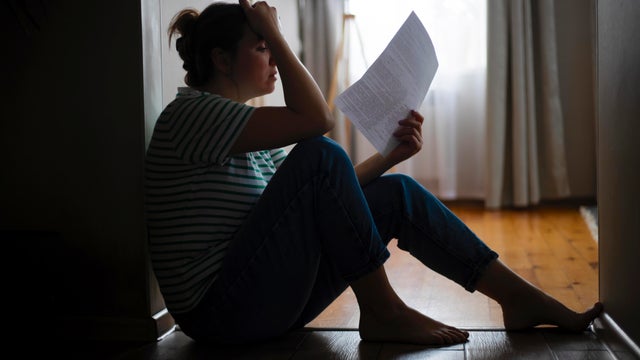 Silhouette of a sad woman sitting on the floor of her apartment 