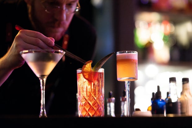A bartender puts the finishing touches on a vibrant cocktail 