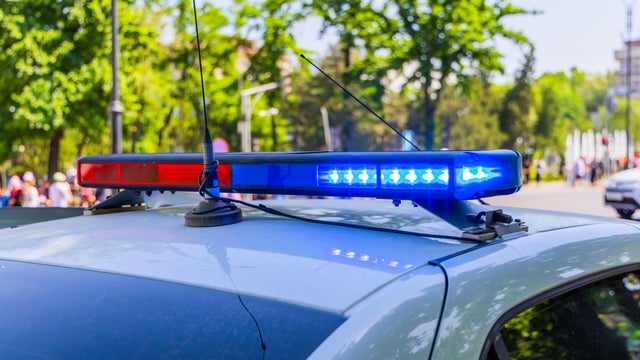 Police vehicle with lights on urban street at sunny summer day 