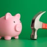 Pink piggy bank face to face hammer on green background. 