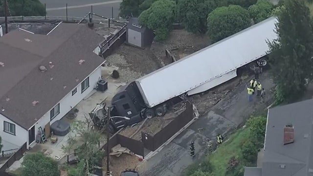 A big rig surrounded by debris from a residential fence near a home 