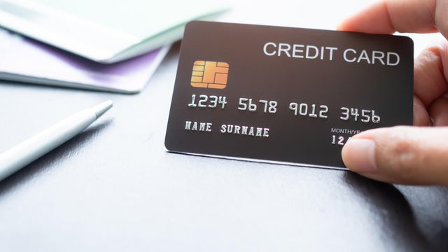 Finger Holding Credit Card with blur bank Account and Pen 