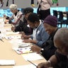 People painting on pieces of paper at a table 