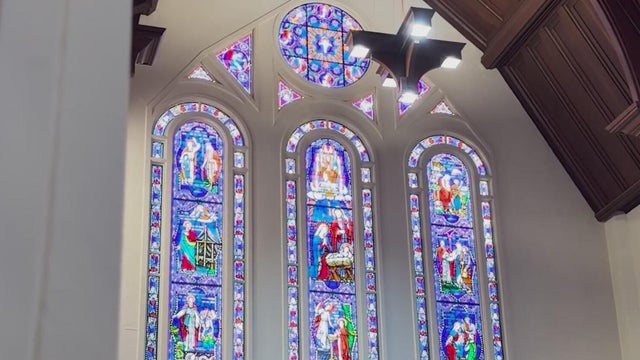 Three stained glass windows are seen from the interior of a church 