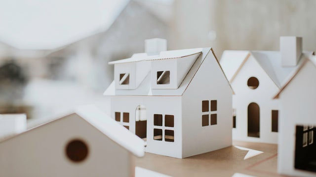Simple image of a village of white cardboard houses in various shapes and sizes 