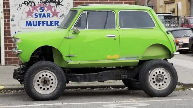 Green mini monster truck parked on street 