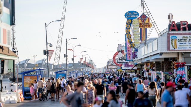 People are on the boardwalk in Wildwood after dark as the tram car goes by 