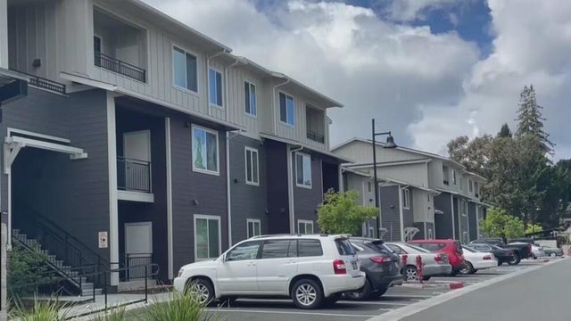 A row of homes with cars parked in front 