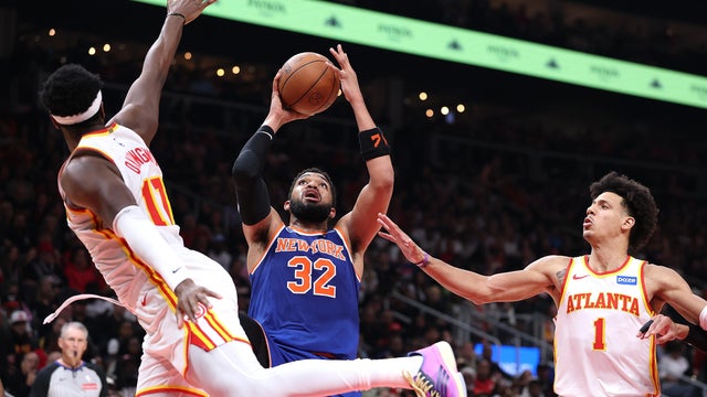 Karl-Anthony Towns #32 of the New York Knicks attempts a shot against Onyeka Okongwu #17 and Jalen Johnson #1 of the Atlanta Hawks during the second quarter of game four of the Eastern Conference first round playoffs at State Farm Arena on April 25, 2026 in Atlanta, Georgia. 