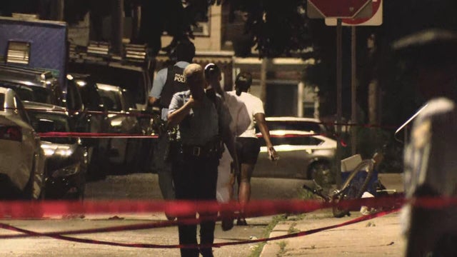 Police officers and red police tape are seen near the scene of the shooting on South Etting Street in Grays Ferry in July 2025 