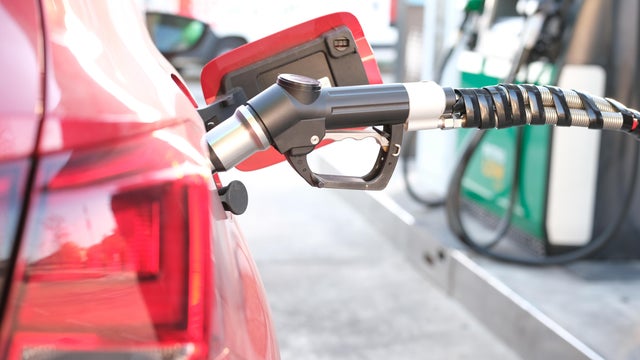 Red car refueling at gas station amid rising fuel prices. Energy crisis and oil dependency - oil price rise 