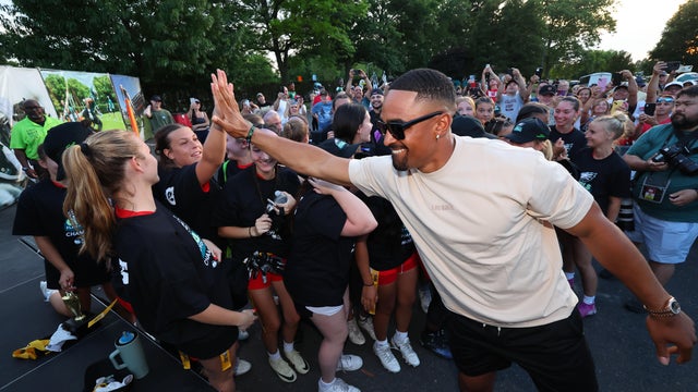 Eagles quarterback Jalen Hurts high fives girls at a flag football event 