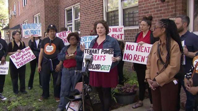 Tenants hold protest signs outside an apartment building 