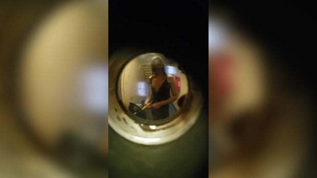 View of individual holding a hatchet through a peephole 