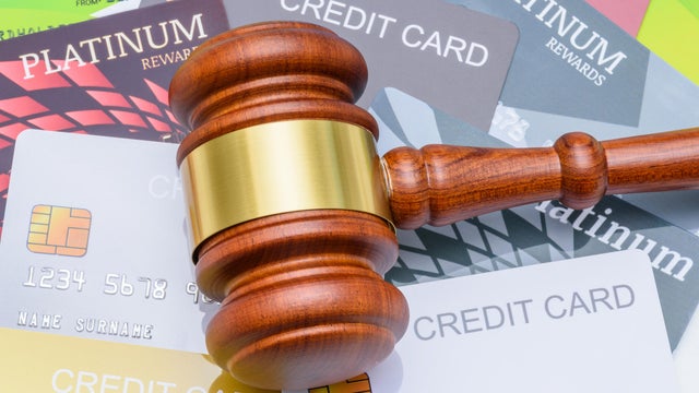 Legal proceedings in financial disputes, credit card debt settlement and financial regulation : A wooden gavel placed on top of many credit cards, depicting regulations surrounding credit and banking. 