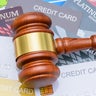 Legal proceedings in financial disputes, credit card debt settlement and financial regulation : A wooden gavel placed on top of many credit cards, depicting regulations surrounding credit and banking. 