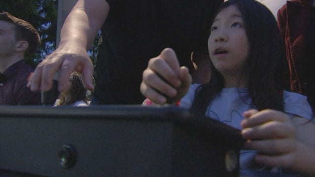 A student looks up at the Cira Centra as she maneuvers the controls of a video game 