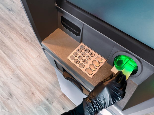 Gloved hand inserting card into ATM machine 