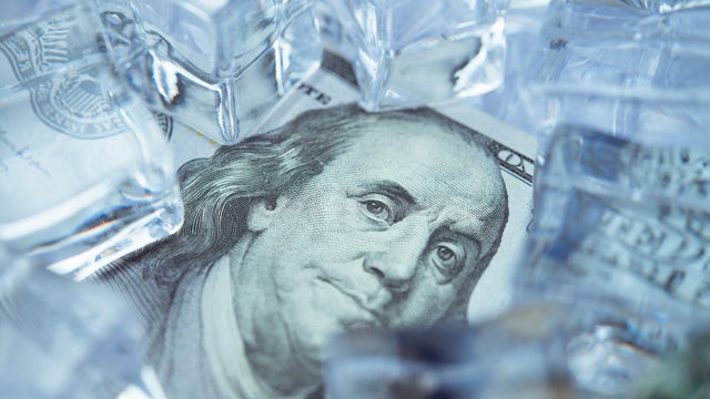 Close up frozen one hundred US dollar bill banknote with ice cubes. 