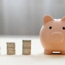 Piggy bank and stack of coins money on wooden background. Save money for prepare in future and pension retirement. Earning interest on savings. Growing your wealth and saving money concept 
