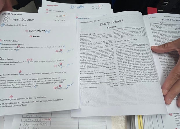 A GPO proofreader compares a page with formatting notations to the final version. 