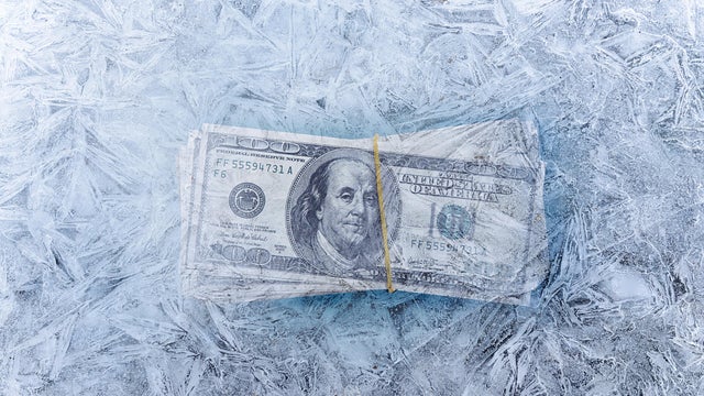 mixed image of frozen dollars in ice cube, global economic crisis and downsizing concepts 
