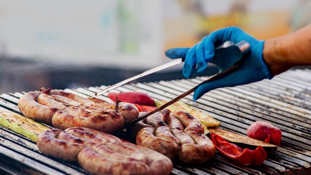 BBQ sausages are grilled over an open fire. Grilled sausages on a charcoal grill. Picnic in the backyard during a family holiday. BBQ food 