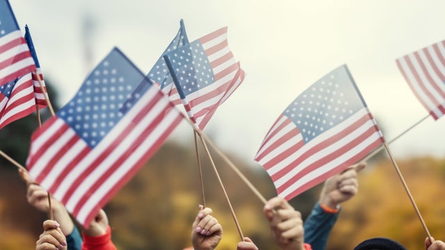 Group of people waving small American flags at sunset. Concept for different topics like Election Results, Happy Veterans Day, Labor Day, Independence Day, President day. 