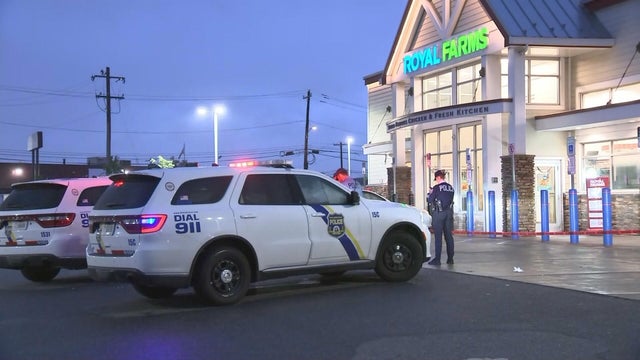 Police cars and personnel outside Royal Farms at dusk 