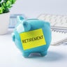 Retirement savings and investment concept with blue piggy bank and office supplies on work table 