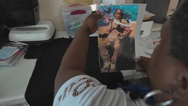 Anita Carrington holds up a picture of her son while making t-shirts 