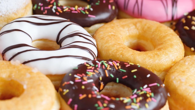 assorted donuts with chocolate frosting, topping sprinkles donuts Colorful variety and Variety of flavors mix of multi colored sweet donuts with frosted sprinkled on pink background. top view 