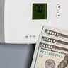 Thermostat for home furnace and air conditioner. Utility bill savings, energy cost and conservation concept 