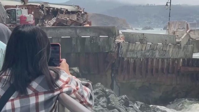a woman takes a photo of a pier 