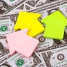 Symbolic miniature houses against the backdrop of US $1 bills 
