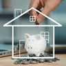 A hand dropping a coin into a piggy bank encased in a white line-art outline of a house, symbolizing the concept of saving money for a home purchase or mortgage. 