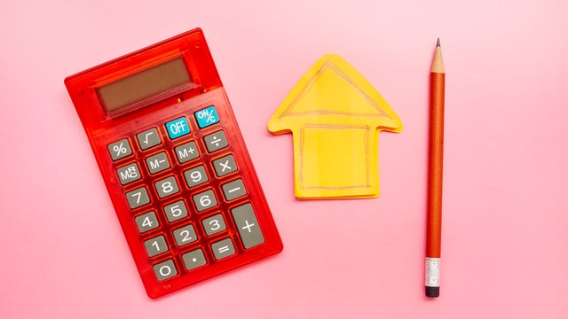 High angle view of calculator, a drawing of a house on an orange notepad and a pencil 
