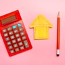 High angle view of calculator, a drawing of a house on an orange notepad and a pencil 