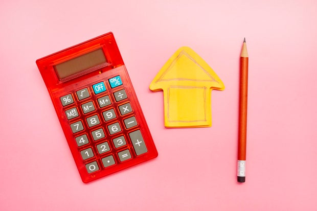 High angle view of calculator, a drawing of a house on an orange notepad and a pencil 
