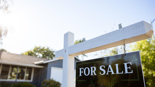 A For Sale sign in front of a house 