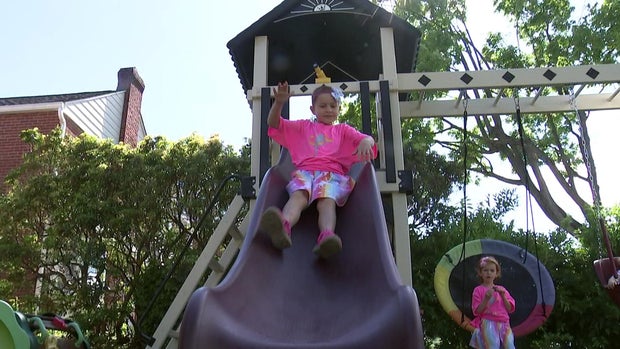 Emilia slides down a slide in her backyard