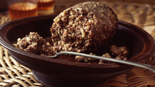 Haggis in bowl on wicker place mat with glasses of whiskey 