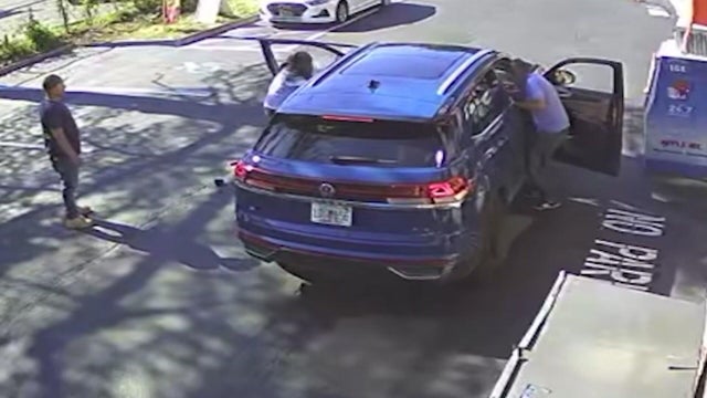 Two men lean into a blue SUV 
