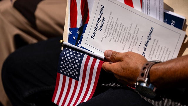 An attendee holds the U.S. flag and lyrics of the national anthem at a naturalization ceremony at George Washington's Mount Vernon in Mount Vernon, Virginia, on July 4, 2025. 
