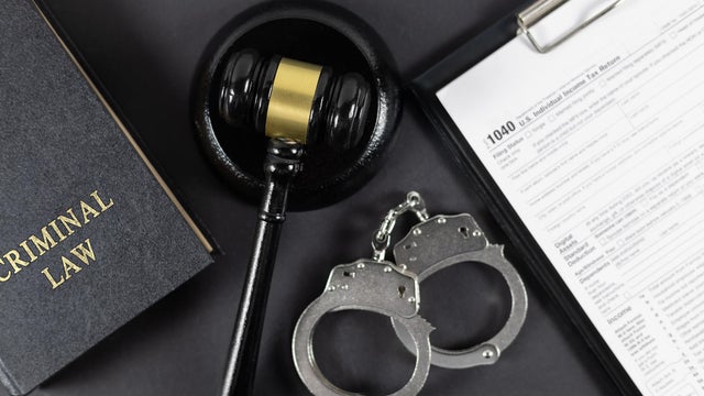 Law book, tax form, judge's gavel and handcuffs on gray textured table 