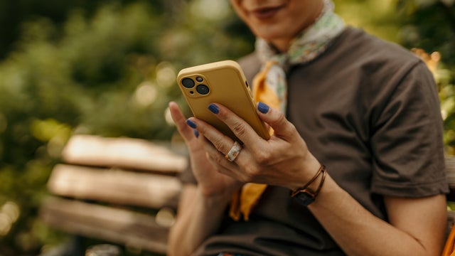 Woman using smartphone while relaxing on park bench 