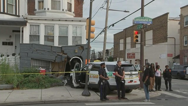 A small SUV taxi is parked outside a house after crashing into it 