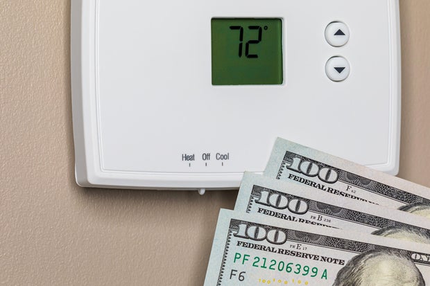 Thermostat for home furnace and air conditioner with cash money. Utility bill savings, energy cost and conservation concept 