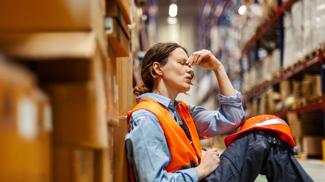 Stressed warehouse worker experiencing burnout in storage facility 